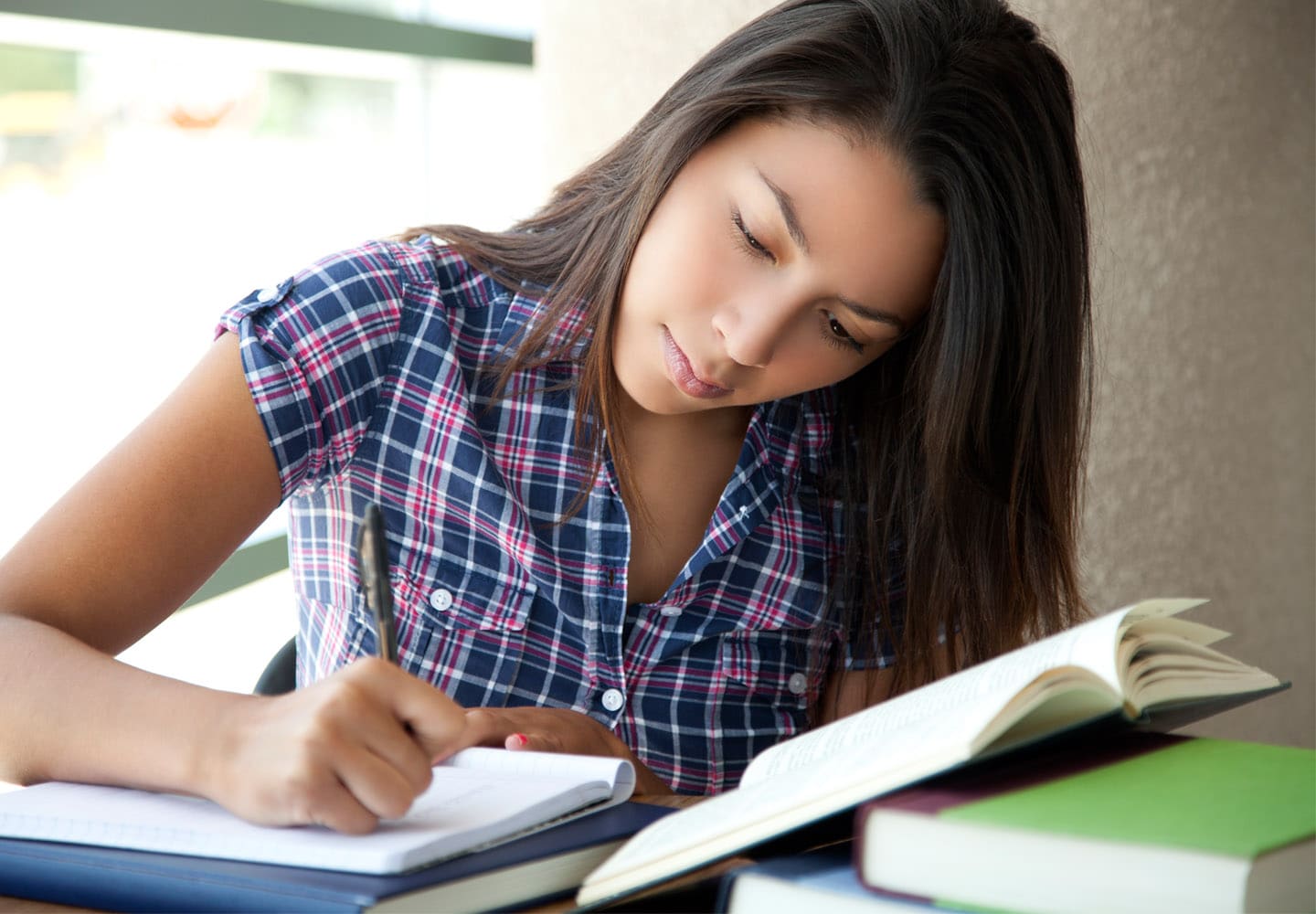 Girl preparing for college and career sitting at desk taking notes from book