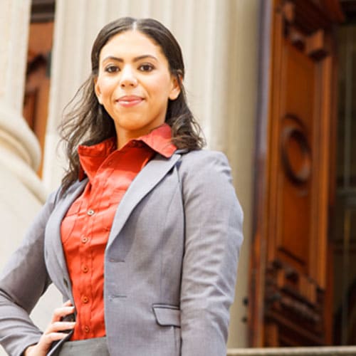 Woman legislator stands proudly on the outdoor marble steps of a government legislative building holding a briefcase